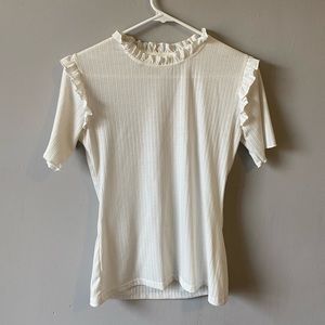 White ribbed t-shirt with ruffles lining the neck and shoulders